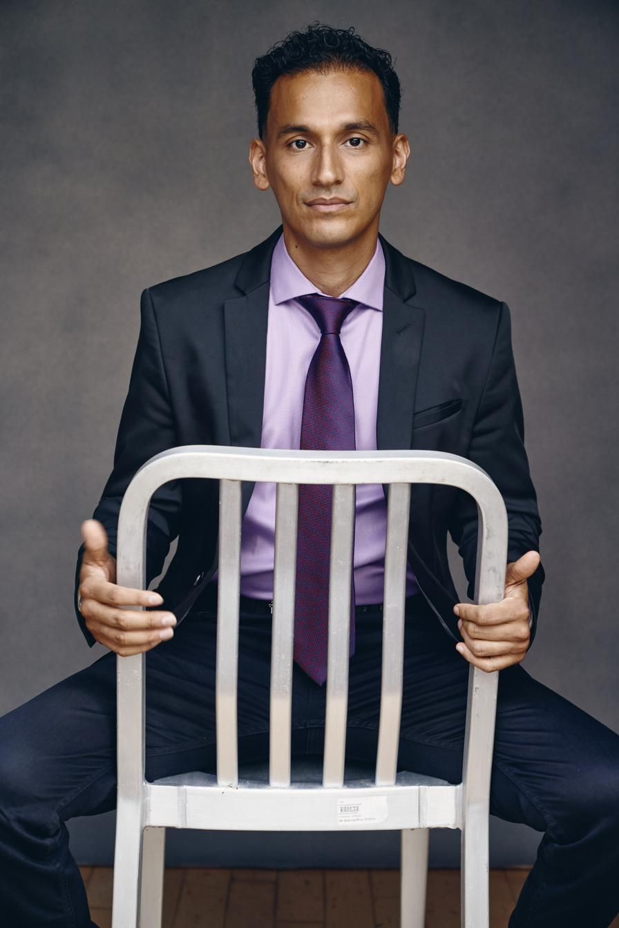 Goya Robles in a suit holding a white chair