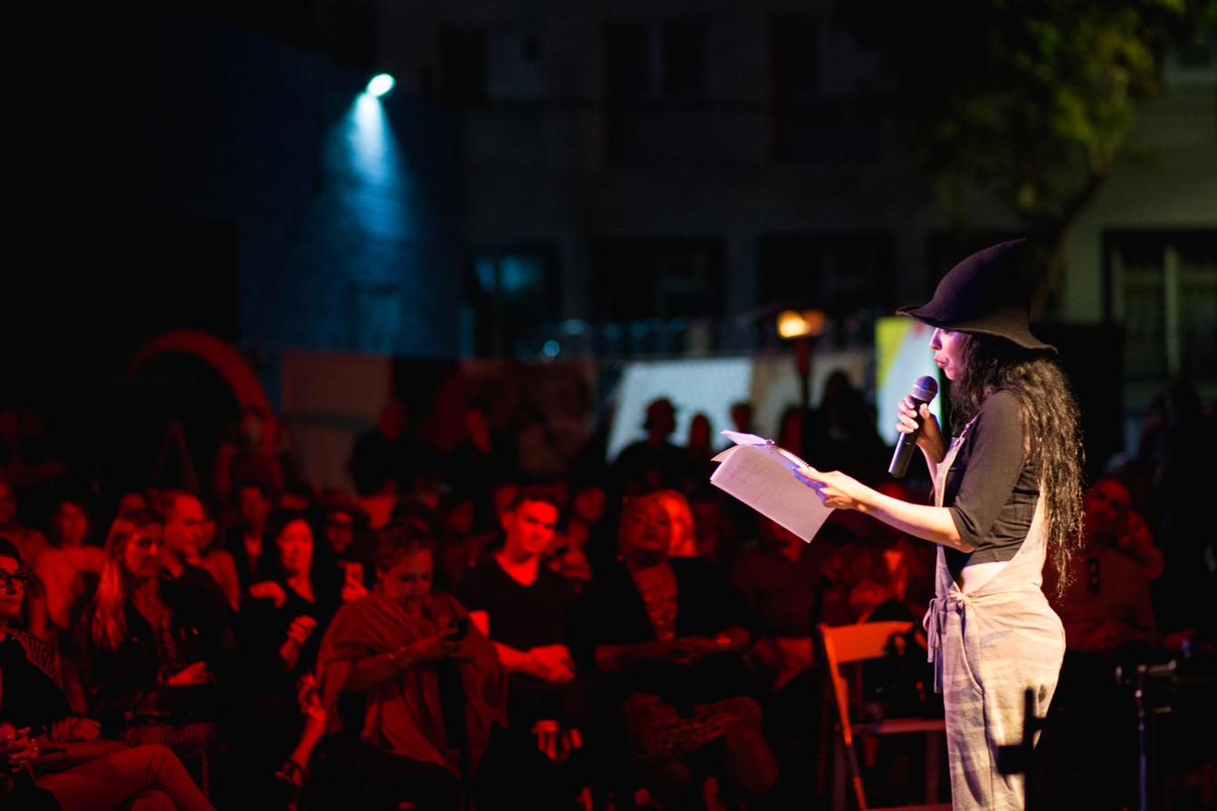 A performer reading into the microphone before the Paint The Mic crowd